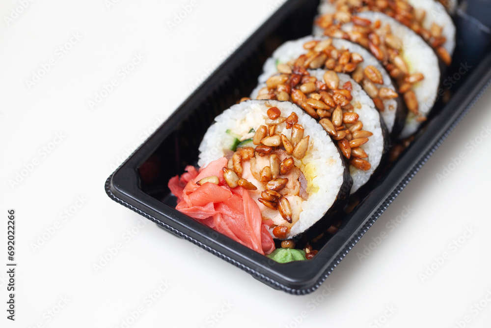 Takeaway sushi background. Sushi roll sprinkled with sunflower seeds. Japanese food isolated on white. Soy sos in plastic container. Sushi box isolated on white. Empty copy space food background. Takeaway sushi background. Sushi roll sprinkled with sunflower seeds. Japanese food isolated on white. Soy sos in plastic container. Sushi box isolated on white. Empty copy space food background.