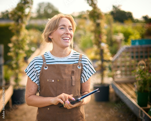 Woman Working Outdoors In Garden Centre Using Digital Tablet