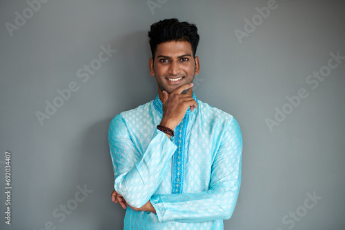 Portrait of confident Indian man in traditional clothes touching chin and smiling at camera photo