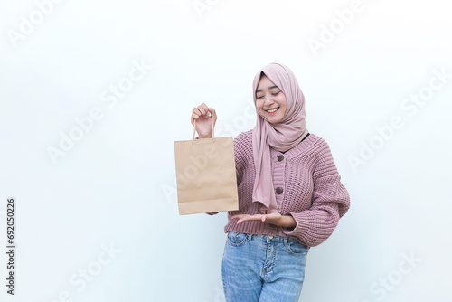A happy beautiful young Asian woman is carrying shopping bag on white background © Mohammad