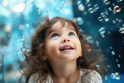 Happy brunette little girl excited looking up in the bubbles