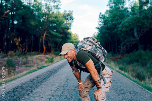 Exhausted middle aged military commando resting while standing on road photo