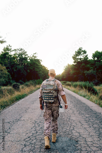 Full body of unrecognizable Mature commando walking on road at sunset photo