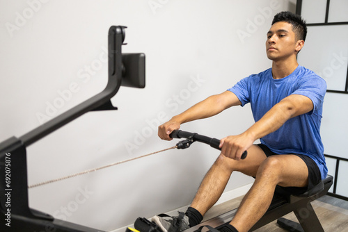 Man focused on rowing machine workout in gym photo