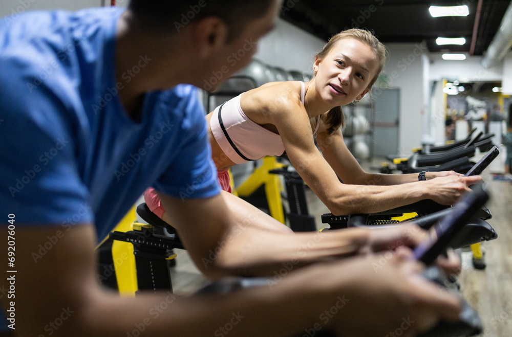 Fitness enthusiasts using stationary bikes at the gym Fitness enthusiasts using stationary bikes at the gym