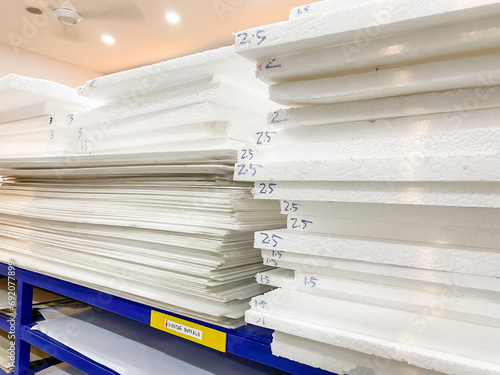 Stack of white foam board sheets of various thicknesses displayed on a shelf in a stationery shop.  Material used for mounting of photographic prints, making  scale models, and painting. photo