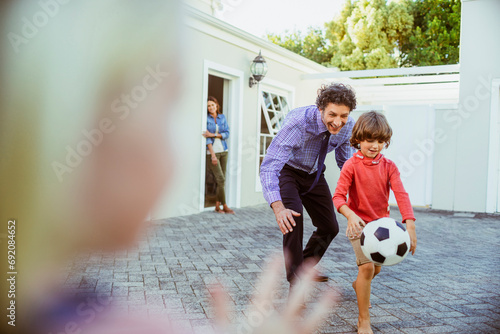 Father and son having fun with soccer ball in backyard photo