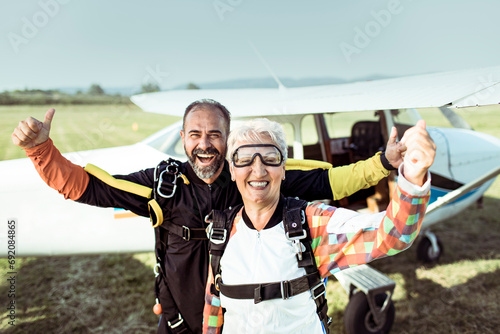 Portrait of happy senior woman and her instructor after skydiving photo