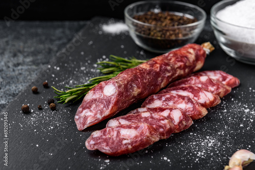 Smoked sausage salami and spices on black background.