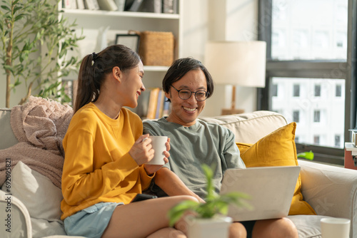 Asian couple family lifestyle,technology concept.Happy young Asian couple using cellphone,watch movie online,browsing internet,chatting online,checking new mobile application,relaxing on sofa at home
 photo