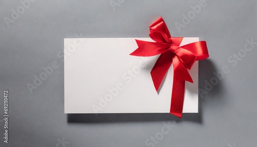 Blank white gift voucher with red ribbon bow or empty gift signboard isolated on grey background with shadow minimal conceptual 