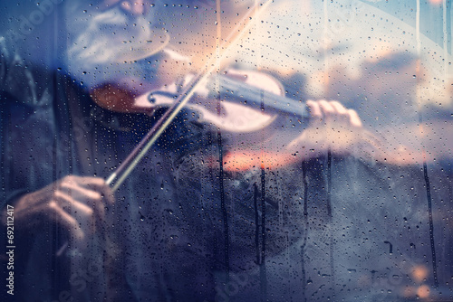 Concepto de violín y música clásica, fondo abstracto. Tocando canción de violín detrás de la ventana con gotas de agua en un día lluvioso. Música triste para el camino de viaje. photo