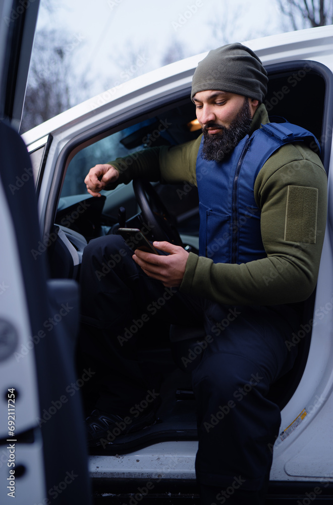 Bearded man wearing body armor sitting in car