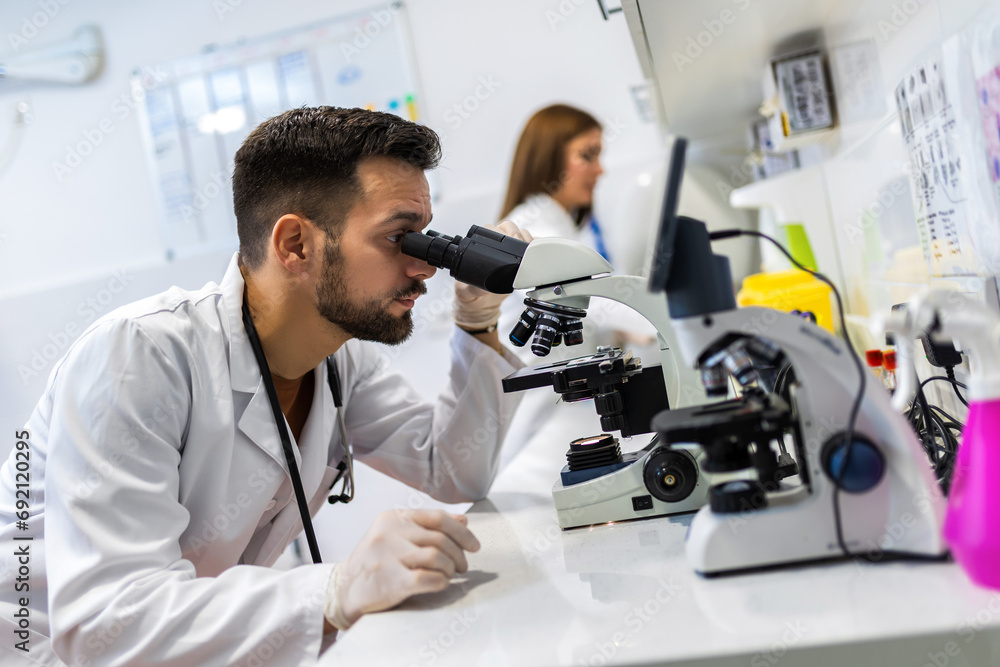 Doctor looking thru microscope while doing research in his lab