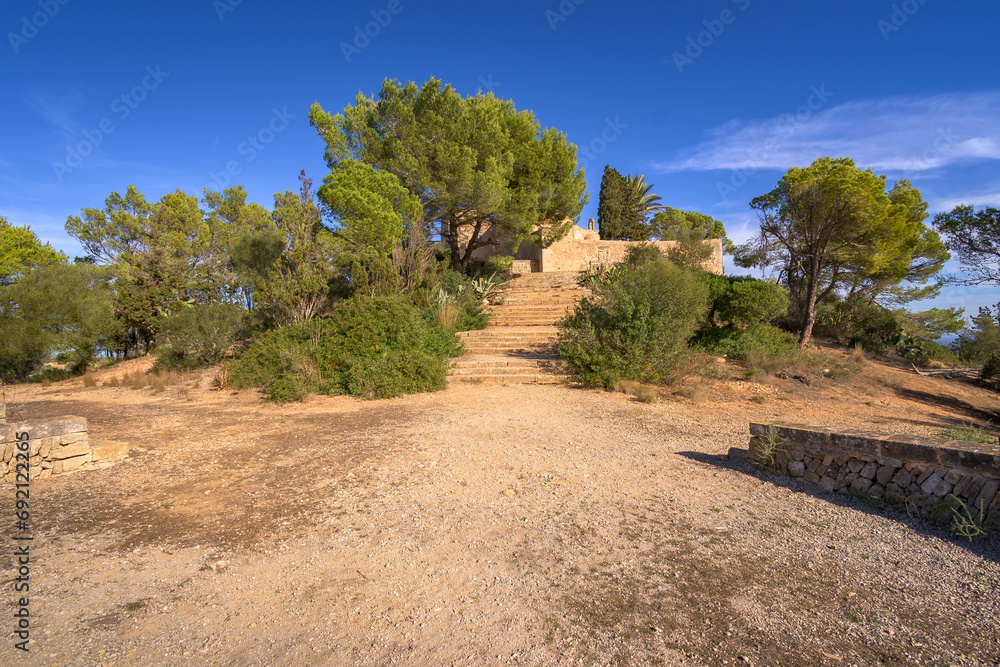 view of the back of a hermitage, or shrine, on a mountaintop surrounded by pine trees in the Balearic Islands.