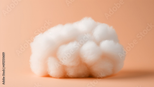 A fluffy white cotton ball on peach fuzz color minimal background. Modern trendy tone hue shade photo