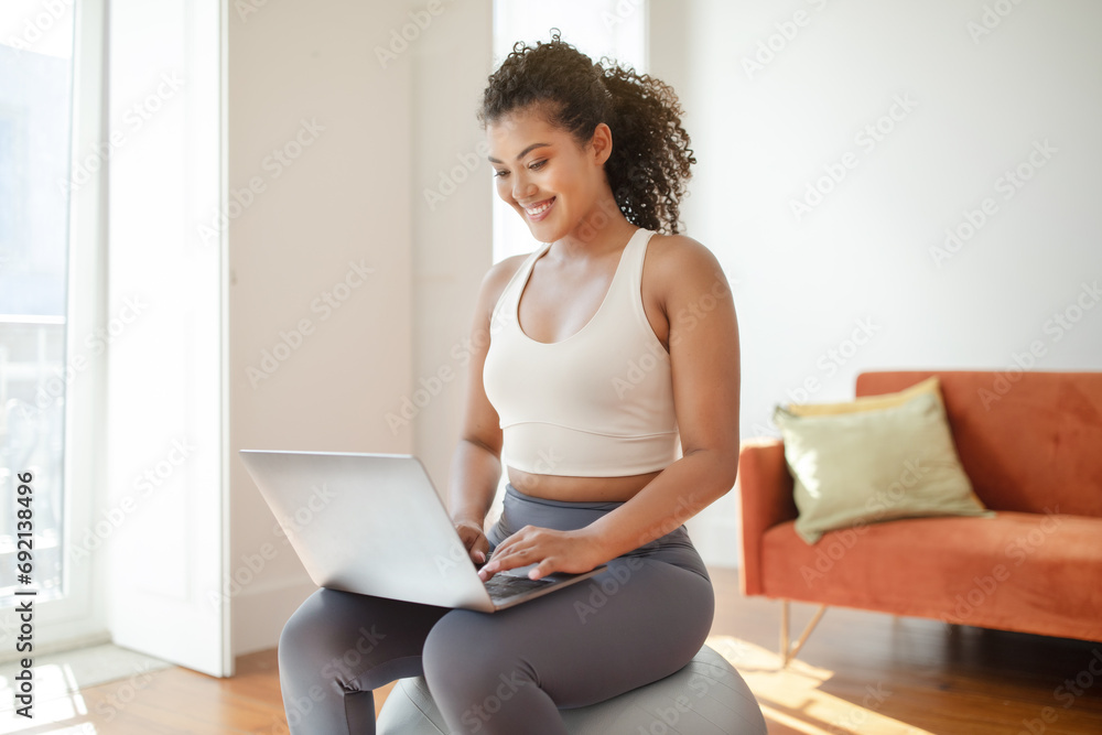 Athletic young woman using laptop for online training videos indoors Athletic young woman using laptop for online training videos indoors