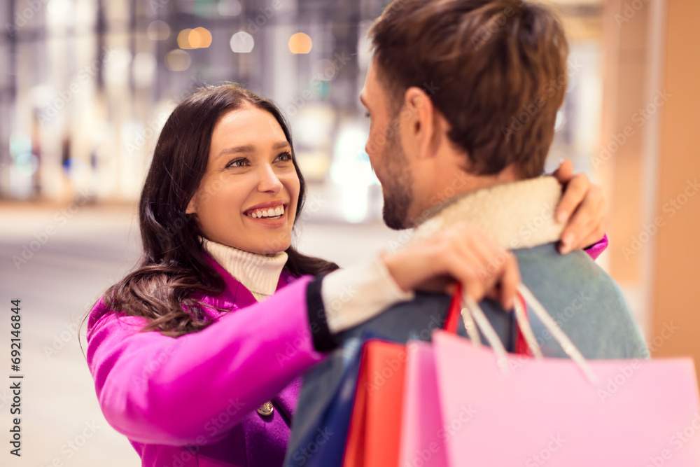 Happy romantic couple enjoying winter spree, shopping outside in evening Happy romantic couple enjoying winter spree, shopping outside in evening