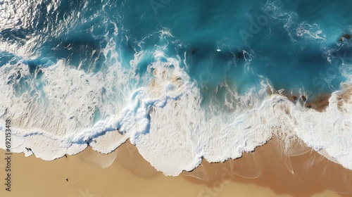 Aerial View of Dynamic Ocean Waves Meeting Sandy Beach with Foamy Elegance under Sunlit Sky