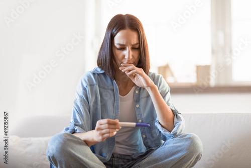 Upset disappointed young european lady holds negative pregnancy test indoor