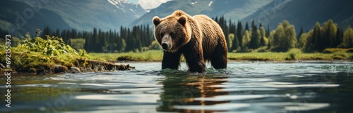 A brown bear wanders along a mountain river against the backdrop of a breathtaking landscape with snow-capped mountain peaks. Concept  a dangerous animal searching for food in the wild near a pond