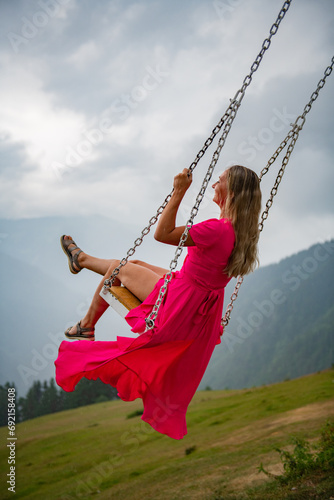 Joyful moments on a swing, a girl in a pink dress on a swing