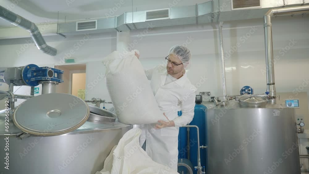 Worker is holding bag with grain ingredient for beer brewing. Pouring malted barley beer ingredient into tank for brewing. Brewing the beer ingredient at the alcoholic drink production facility Worker is holding bag with grain ingredient for beer brewing. Pouring malted barley beer ingredient into tank for brewing. Brewing the beer ingredient at the alcoholic drink production facility