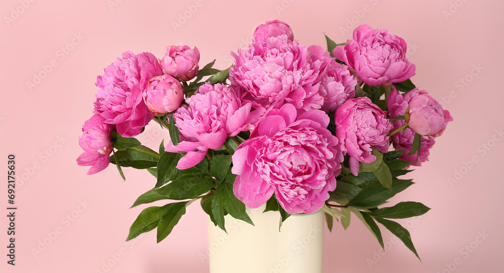 Vase with fresh peonies on pink background