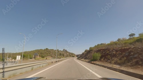 First person view, FPV, from dashcam of car driving along the Algarve Coast in Portugal, driving on the highway towards Faro. Road trip video in POV, with blue sky	 photo