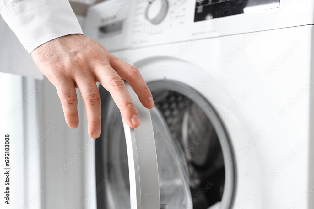 Young man opening washing machine, closeup Young man opening washing machine, closeup