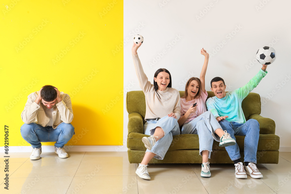Young man suffering from loud neighbours watching sport game at home Young man suffering from loud neighbours watching sport game at home