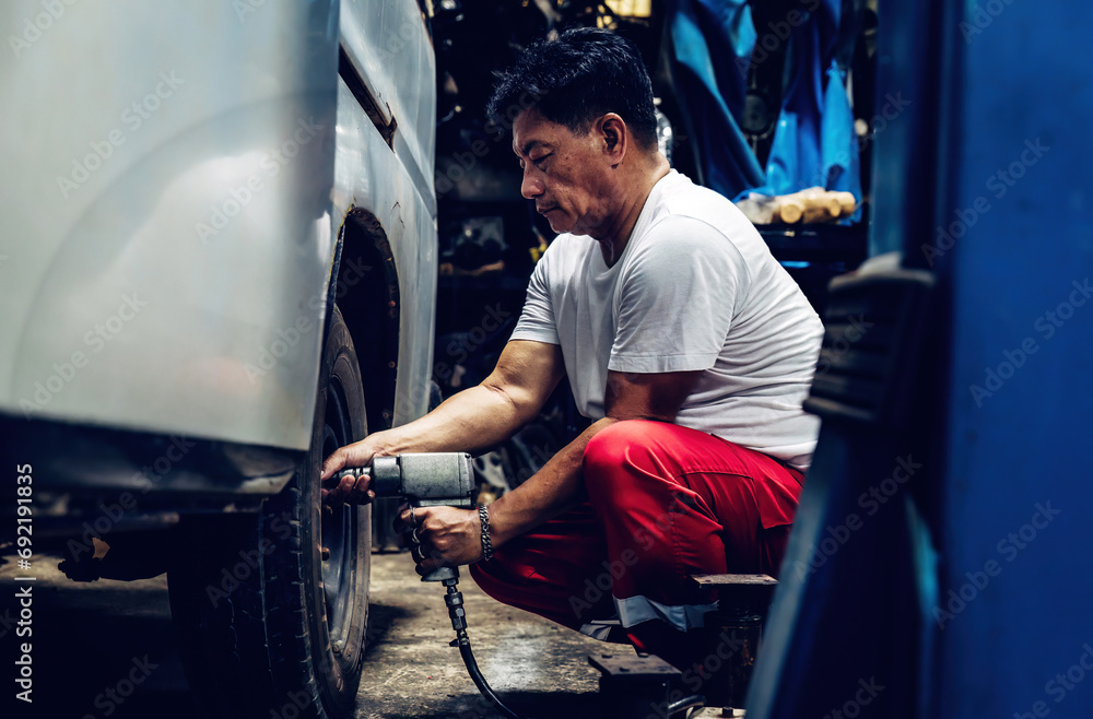 Mechanician changing car wheel in auto repair shop. changing wheels/tires. Concept of car care service and maintenance or fix the car Mechanician changing car wheel in auto repair shop. changing wheels/tires. Concept of car care service and maintenance or fix the car