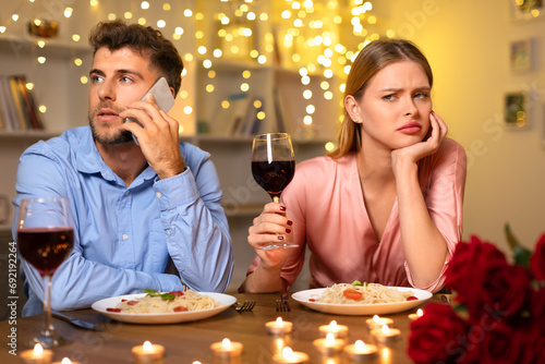 Distracted man on phone  woman upset at romantic dinner