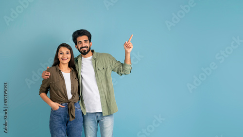 Positive indian couple showing blank space for advertisement