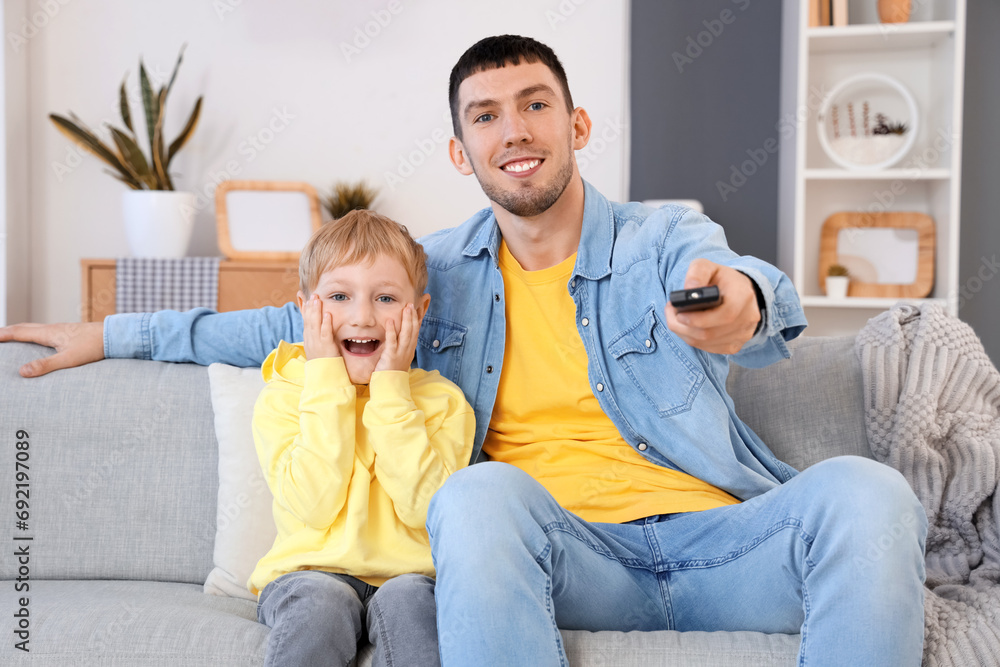 Little boy with his father watching TV at home