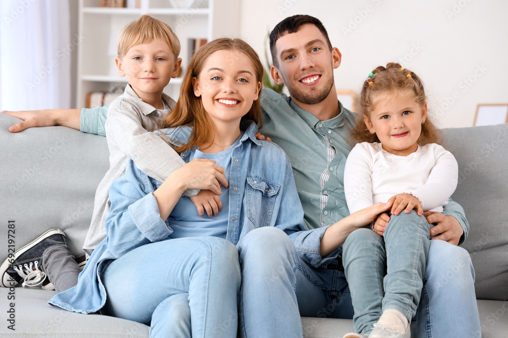 Happy little children with their parents hugging on sofa at home