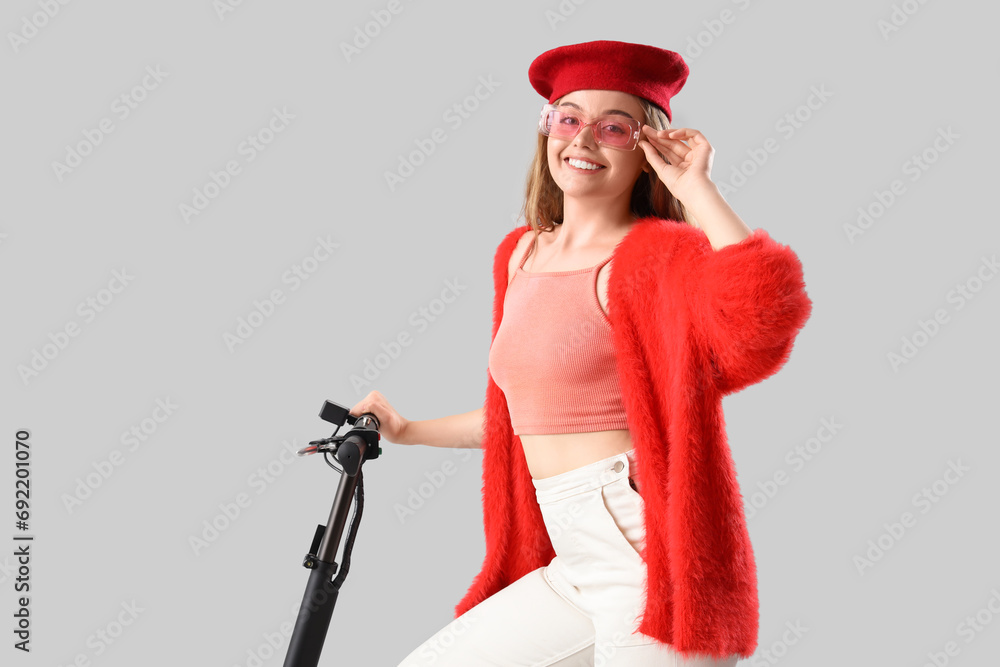Stylish young woman with electric scooter on light background Stylish young woman with electric scooter on light background