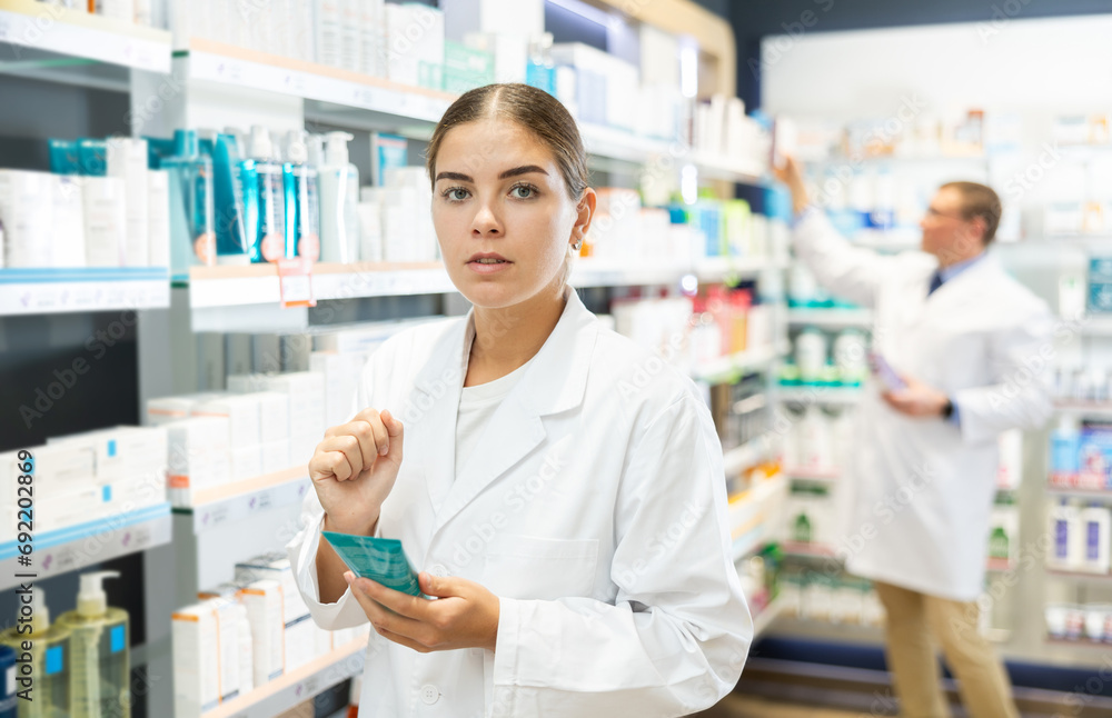Girl pharmacist carefully reads the information on the label of a medicinal intimate hygiene in a pharmacy