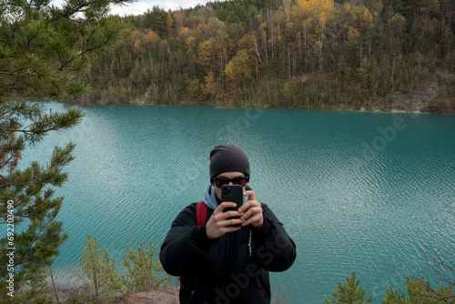 A tourist takes pictures of the turquoise water of the lake and takes a selfie