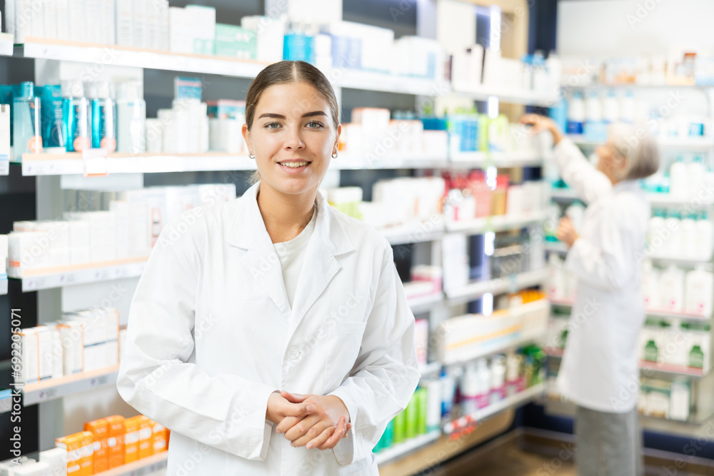Young female pharmacist in medical uniform posing while working in pharmacy
