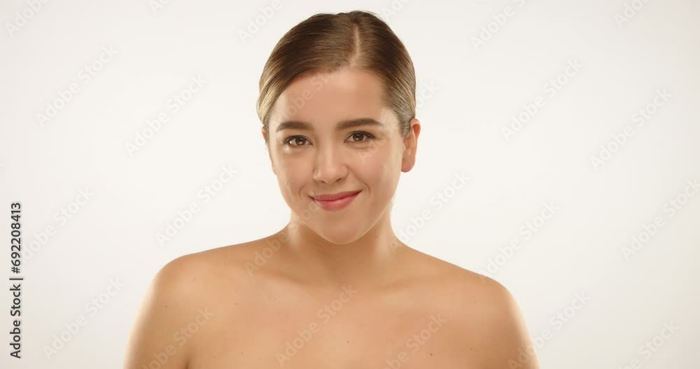 Close up of a young beautiful girl smiling at the camera and appearing slightly shy. She is in soft studio lighting with a white background. High quality 4k footage. Close up of a young beautiful girl smiling at the camera and appearing slightly shy. She is in soft studio lighting with a white background. High quality 4k footage.