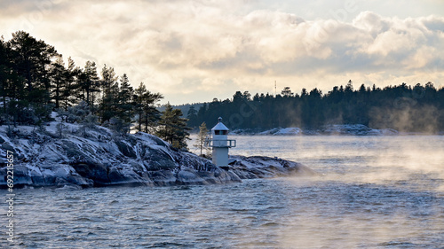 Biały znak nawigacyjny na skalistej wyspie otoczonej wodą w archipelagu wysp Alandzkich w Finlandii w mroźnej i zimowej aurze.