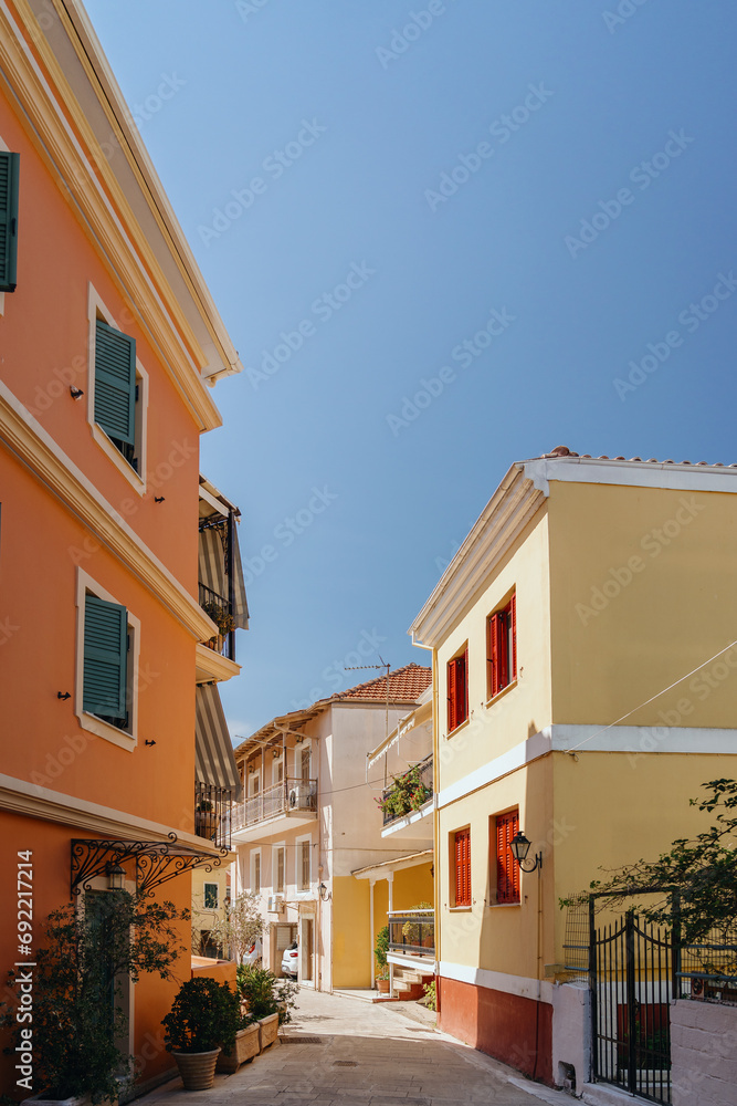 A picturesque view of a quiet, sunlit alley framed by colorful houses with shutters, in a Mediterranean village