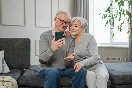 Video call. Happy senior couple woman man with smartphone having video call. Mature old grandmother grandfather talking speaking online. Older generation modern tech usage. Virtual meeting online chat
