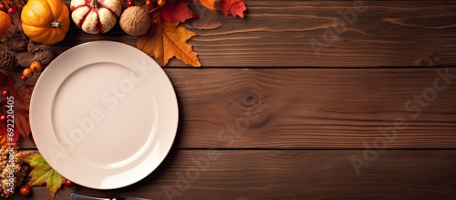 Autumn fall or thanksgiving table setting design captured from above top view flat lay White plate glass cutlery and decorations colorful leaves Dark moody light. Copy space image