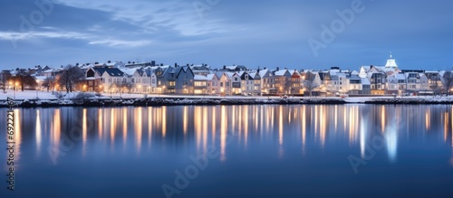 Beautiful houses reflected in lake Tjornin in Reykjavik Iceland during the blue hour in winter. Copy space image. Place for adding text or design © Ilgun