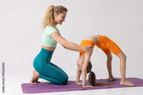 mother and daughter do sports and gymnastics on a white background, two girls do fitness photo