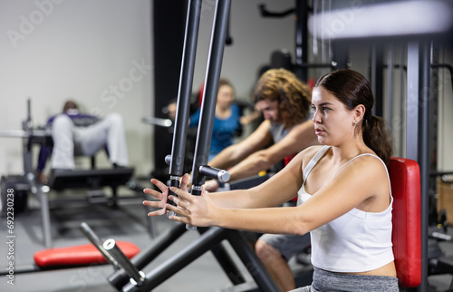 Caucasian woman doing exercises on chest fly machine in gym