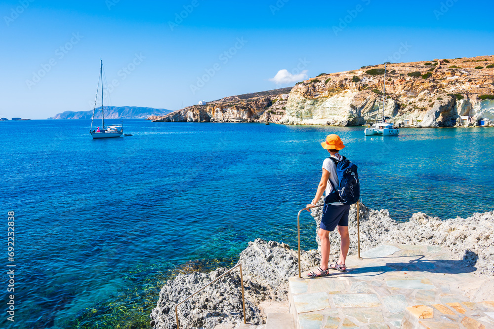 Young woman tourist looking at Rema beach in beautiful sea bay, Kimolos island, Cyclades, Greece - obrazy, fototapety, plakaty 
