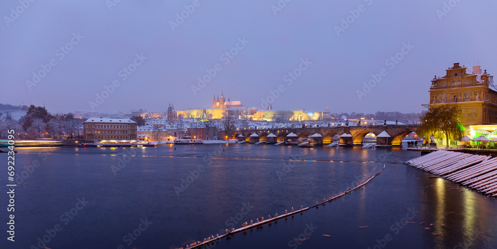 Night snowy Prague Lesser Town with gothic Castle, St. Nicholas' Cathedral and Charles Bridge, Czech republic